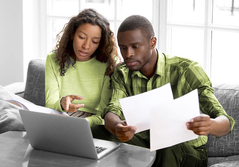 African American couple at laptop with bills